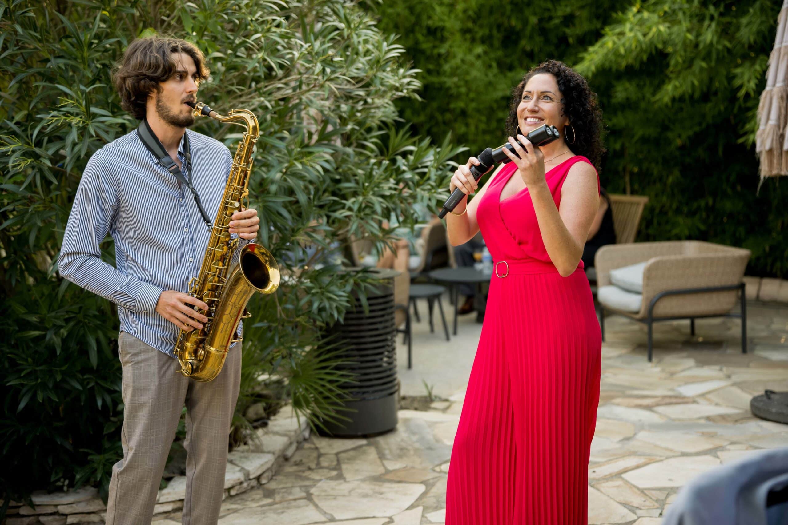 Saxophoniste et chanteuse en combinaison rouge lors d'une performance de jazz live en extérieur.